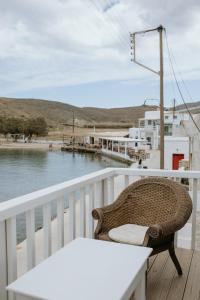 a wicker chair sitting on a balcony next to the water at Yi & Thalassa Living by KHI in Kithnos