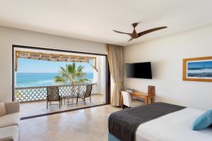 a bedroom with a bed and a balcony with the ocean at Cabo Surf Hotel in San José del Cabo