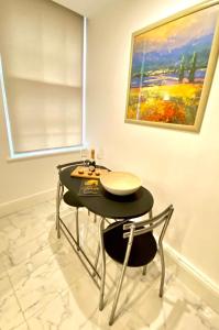 Remarkable Apartment in London في لندن: غرفة طعام مع طاولة و كرسيين و لوحة