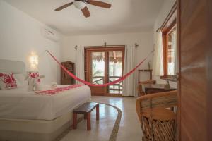 un dormitorio con una cama con una cuerda roja alrededor en Casa Iguana Holbox - Beachfront Hotel, en Isla Holbox