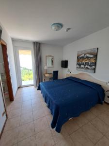 a bedroom with a blue bed and a window at Hotel Laguna in San Zeno di Montagna