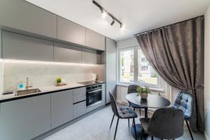 a kitchen with a table and chairs and a window at Grey Apartments in Šiauliai