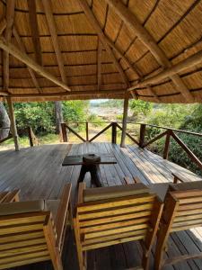 una mesa de madera y sillas en una terraza de madera en Bua River Lodge 