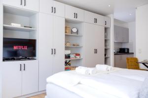 a white bedroom with a bed and a tv at Lumen Homes - Altstadt-Studio direkt im Zentrum, Küche, öffentlicher Parkplatz ums Eck in Ingolstadt +50 photos