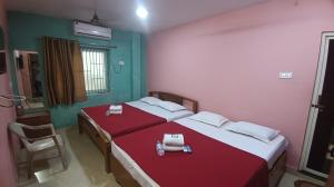 two beds in a room with red and green walls at hotel sudhara in Tirukkadaiyūr