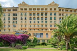 a large building with palm trees and purple flowers at Le COQ Tersling - Residential Parking - AC - Sea view in Menton