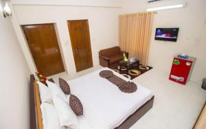 a bedroom with a bed and a chair and a television at Hotel Suite Palace Baridhara in Dhaka