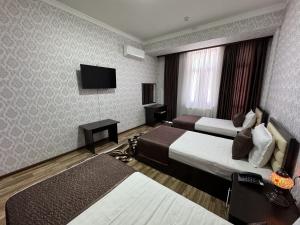 a hotel room with two beds and a flat screen tv at Al-Khabib in Bukhara
