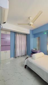 1 dormitorio con cama y pared azul en Baridhara Sweet Home, en Dhaka
