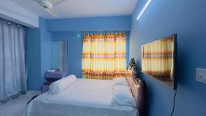 Dormitorio azul con cama y ventana en Baridhara Sweet Home, en Dhaka