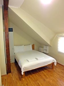 a bedroom with a white bed in an attic at Nika's House Trosobna kuća sa trpezarijom i kuhinjom,u skopu jos dva apartmana,bazen,terasa i sauna in Palić