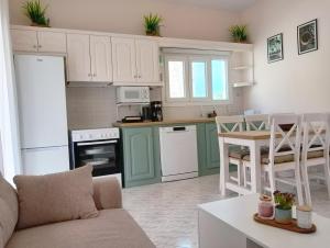 a kitchen with green and white cabinets and a table at Voula's maisonette in Acharavi