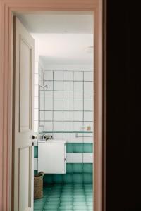 a bathroom with a white sink and green tiles at Posillipo 70 Napoli in Naples