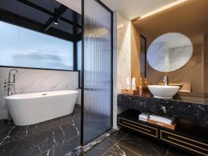 a bathroom with a tub and a sink and a mirror at Minerva Premium Hotel in Hanoi