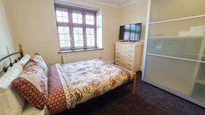 a bedroom with a bed and a dresser with a tv at Luxury London House Sleeps x 16, Free Parking, Free Wifi, Garden Patio, Close to tube line easy access to Central London in Ilford