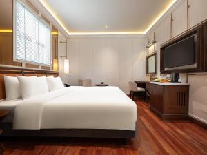 a hotel room with a large white bed and a desk at Minerva Premium Hotel in Hanoi