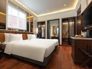 a bedroom with a large white bed and a television at Minerva Premium Hotel in Hanoi