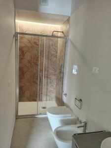uma casa de banho com 2 WC e uma cabina de duche em vidro. em Aura Apartments em Mattinata