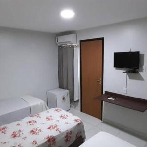 Habitación de hotel con cama y TV en Mandacaru pousada en Maceió