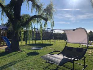 una silla junto a un árbol con parque infantil en Parc de la Charmille, en Saint-Étienne-sur-Reyssouze