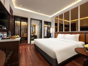 a bedroom with a large white bed and a kitchen at Minerva Premium Hotel in Hanoi