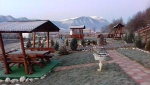 Dumbrava Ursului في زارنيشتي: حديقة بها مقاعد وملعب مع جبال في الخلفية