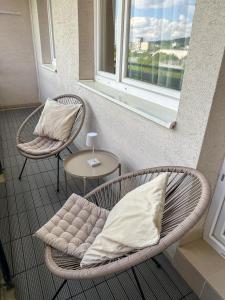 silla de mimbre con almohada y mesa con ventana en Apartmán Simcity Bratislava en Bratislava