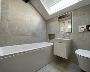a bathroom with a tub and a toilet and a sink at Daisy Cottage in Keswick +16 photos