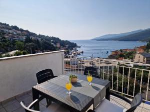 a table on a balcony with a view of the water at Apartment Nadija in Rabac