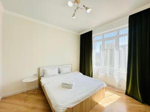 ein Schlafzimmer mit einem Bett und einem großen Fenster in der Unterkunft Grand Turan Comfort Two-Room Apartments in Astana