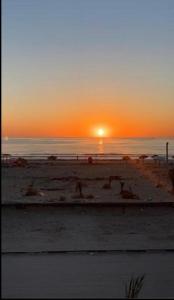 un tramonto su una spiaggia con il sole che tramonta sull'oceano di Appartement Vue de Mer Pied dans l'eau a Gabès