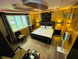POLO LAND HOTEL Skardu في Tandal: غرفة نوم مع سرير ومكتب مع مروحة