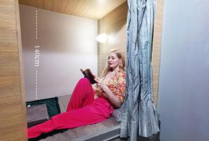 a woman sitting on a couch reading a book at SUSU khaosan hostel in Bangkok