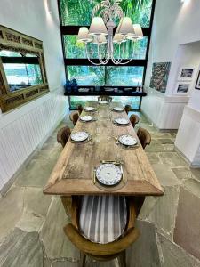 a dining room with a long table with chairs and a chandelier at Mansao Angra Pe na Areia in Angra dos Reis