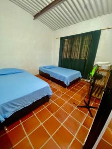 two beds in a room with a tiled floor at El Palmar in Guaduas