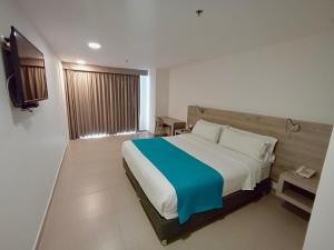 1 dormitorio con 1 cama grande y TV en VVC Hotel's, en Villavicencio