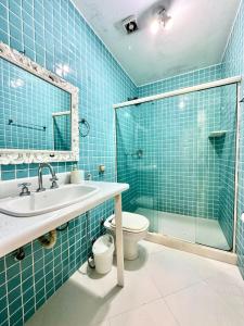 a blue tiled bathroom with a sink and a toilet at Mansao Angra Pe na Areia in Angra dos Reis