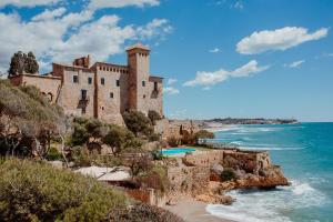 a castle on a cliff next to the ocean at Camping Caledonia in Tamarit