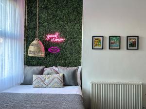 a bedroom with a bed with a green wall with a neon sign at J&W Apartments with free parking in Liverpool