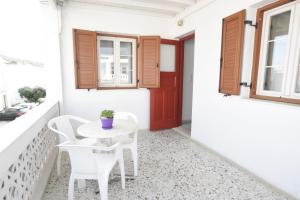 d'une petite table et de chaises blanches sur un balcon avec une porte rouge. dans l'établissement Asteri Hotel, à Ornos