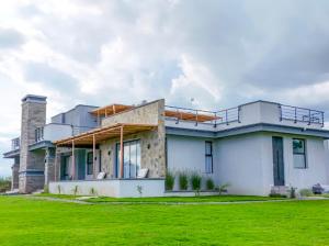 una casa grande con un campo verde delante de ella en Impala House, en Naivasha