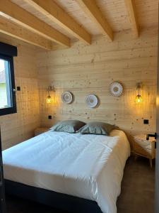 a bedroom with a white bed in a wooden wall at Les Chalets près de Chalain in Montigny-sur-lʼAin