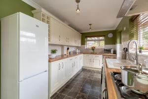 cocina con armarios blancos y nevera blanca en Three Bedroom Apartment - Contractors & Groups welcome in Northampton by Centro Stays - Free WiFi & Parking en Northampton