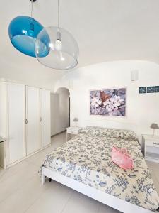 a white bedroom with a bed and a blue chandelier at Maridea - Insvla in Ponza