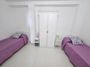 two beds in a white room with purple sheets at Maridea - Insvla in Ponza +14 photos