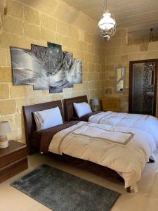 1 dormitorio con 1 cama grande y pared de piedra en Daner Ta’ Pantu House, en Kerċem