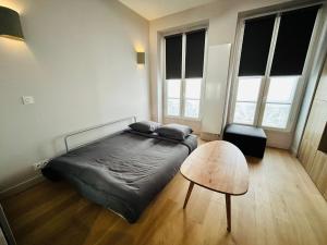 a bedroom with a bed and a table and windows at New studio fully furnished - Rue d'Enghien, Paris in Paris