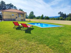 two red chairs sitting next to a swimming pool at Casa Fronteiriça - 2 Casas com piscina privada in Valença