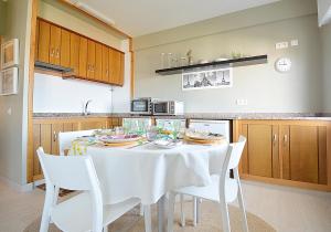 Apartamento con parking en San Vicente في او غروف: مطبخ مع طاولة بيضاء وكراسي بيضاء +5 صور