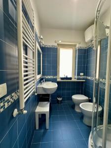 Baño de azulejos azules con 2 aseos y lavamanos en La Marina B&B, en Civitavecchia